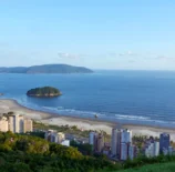 Vista aérea da cidade de Santos, localizada no litoral do estado de São Paulo, Brasil, com prédios e áreas verdes visíveis. A fotografia ilustra a questão do aquecimento dos oceanos que desafia as cidades costeiras.