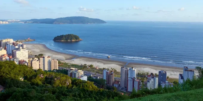 Vista aérea da cidade de Santos, localizada no litoral do estado de São Paulo, Brasil, com prédios e áreas verdes visíveis. A fotografia ilustra a questão do aquecimento dos oceanos que desafia as cidades costeiras.