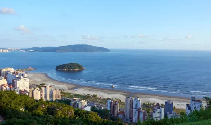 Vista aérea da cidade de Santos, localizada no litoral do estado de São Paulo, Brasil, com prédios e áreas verdes visíveis. A fotografia ilustra a questão do aquecimento dos oceanos que desafia as cidades costeiras.