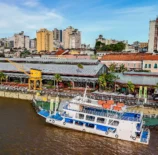 Cena de Belém durante a COP30 mostrando o rio, edifícios e um barco ecológico, promovendo o financiamento climático no contexto de sustentabilidade e mudanças climáticas.