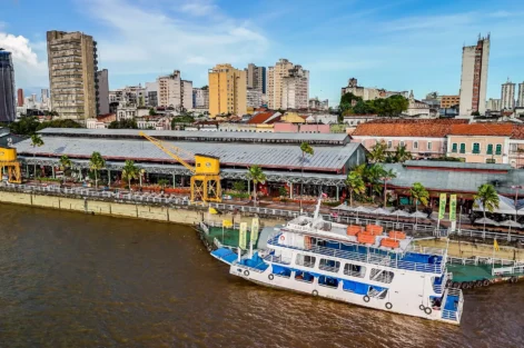 Cena de Belém durante a COP30 mostrando o rio, edifícios e um barco ecológico, promovendo o financiamento climático no contexto de sustentabilidade e mudanças climáticas.