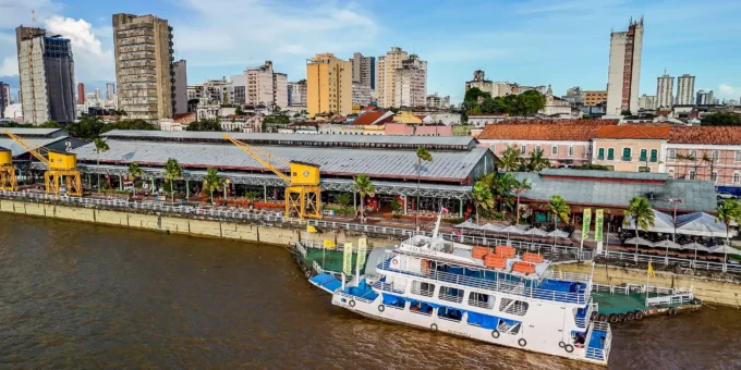 Cena de Belém durante a COP30 mostrando o rio, edifícios e um barco ecológico, promovendo o financiamento climático no contexto de sustentabilidade e mudanças climáticas.