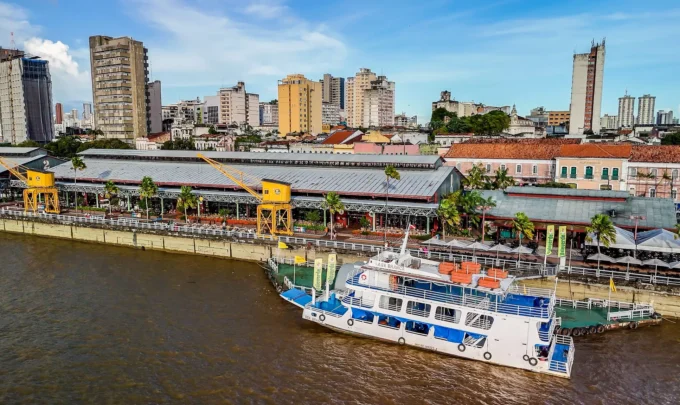 Cena de Belém durante a COP30 mostrando o rio, edifícios e um barco ecológico, promovendo o financiamento climático no contexto de sustentabilidade e mudanças climáticas.