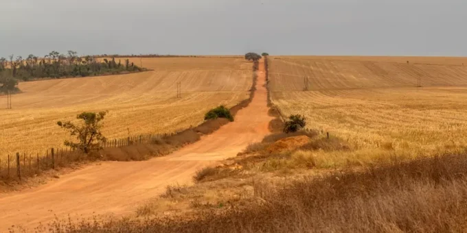 Cenário de desmatamento e degradação ambiental em uma paisagem agrícola, representando os desafios da justiça climática e os impactos das mudanças climáticas na terra.