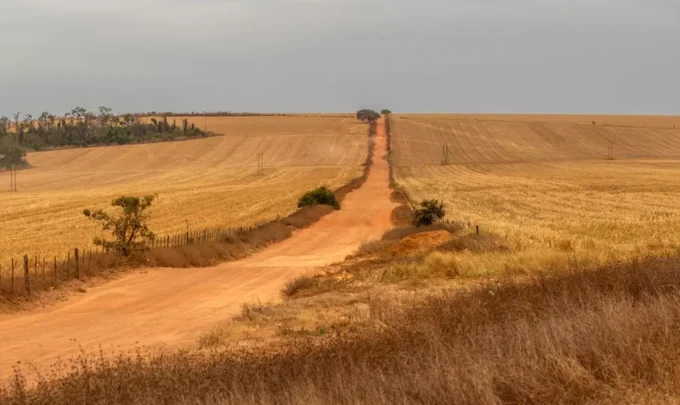 Cenário de desmatamento e degradação ambiental em uma paisagem agrícola, representando os desafios da justiça climática e os impactos das mudanças climáticas na terra.