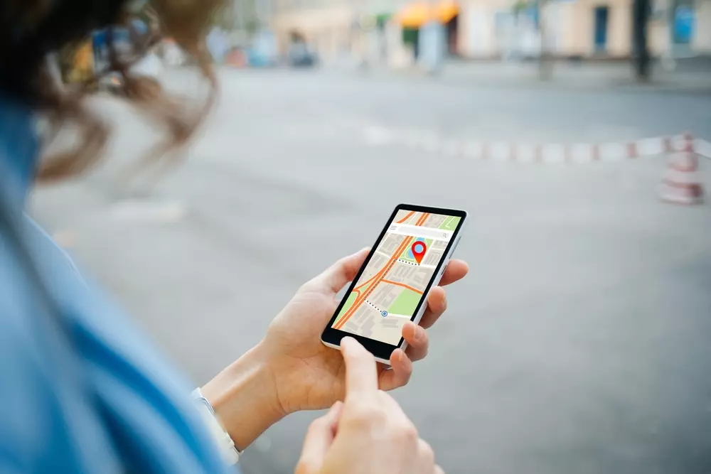 Mulher utilizando smartphone com mapa para fomentar o forrageamento urbano na cidade, promovendo práticas sustentáveis e integrar a natureza às áreas urbanas.