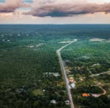 Vista aérea da Ilha de Marajó com vastas áreas de vegetação verde, estrada principal e céu com nuvens, destacando um refúgio verde na natureza amazônica.