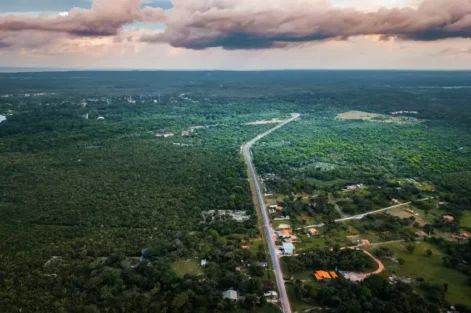 Vista aérea da Ilha de Marajó com vastas áreas de vegetação verde, estrada principal e céu com nuvens, destacando um refúgio verde na natureza amazônica.