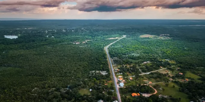 Vista aérea da Ilha de Marajó com vastas áreas de vegetação verde, estrada principal e céu com nuvens, destacando um refúgio verde na natureza amazônica.