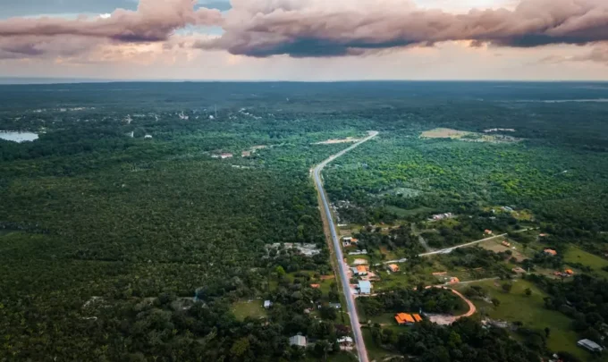 Vista aérea da Ilha de Marajó com vastas áreas de vegetação verde, estrada principal e céu com nuvens, destacando um refúgio verde na natureza amazônica.