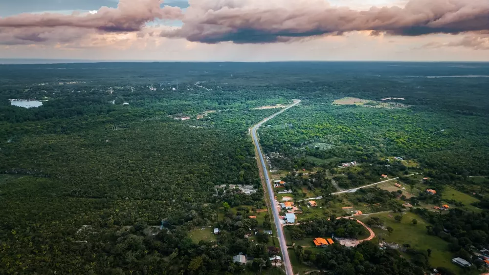 Vista aérea da Ilha de Marajó com vastas áreas de vegetação verde, estrada principal e céu com nuvens, destacando um refúgio verde na natureza amazônica.