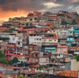 Vista da arquitetura da quebrada na favela do Rio de Janeiro ao entardecer, mostrando casas coloridas empilhadas em um morro.