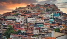 Vista da arquitetura da quebrada na favela do Rio de Janeiro ao entardecer, mostrando casas coloridas empilhadas em um morro.