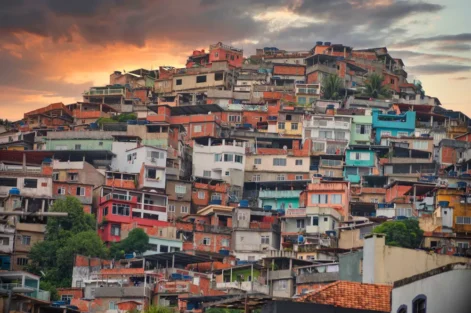 Vista da arquitetura da quebrada na favela do Rio de Janeiro ao entardecer, mostrando casas coloridas empilhadas em um morro.