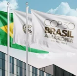 Bandeiras do Brasil e da COP Brasil Amazônia tremulam em frente a um prédio moderno durante o evento COP30 em Belém, onde foram estabelecidos os primeiros padrões globais para edificações sustentáveis e resilientes.