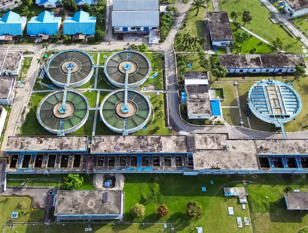 Vista aérea de uma estação de tratamento de água com tanques circulares e infraestrutura.
