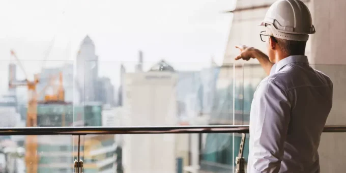 Profissional de construção civil analisando projeto de Lean Construction em um ambiente moderno de escritórios com vista para a cidade