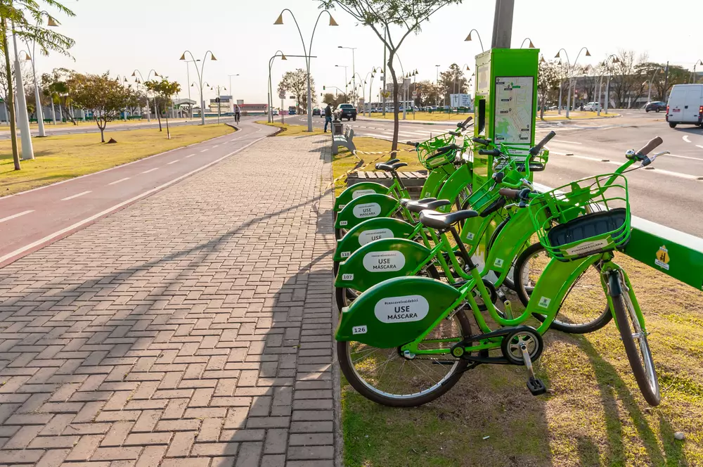 Bairro sustentável com sistema de transporte de bicicletas compartilhadas em um ambiente de mobilidade urbana inteligente, com vias bem cuidadas e áreas verdes.