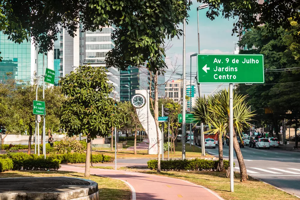ua com sinais de trânsito, árvores, ciclovia e edifícios comerciais