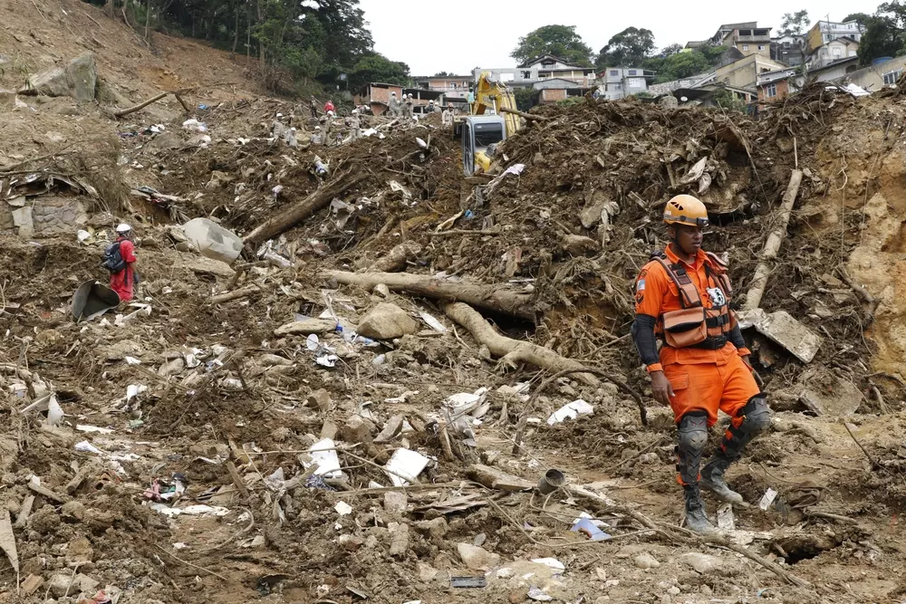 Deslizamento de terra na cidade de Petrópolis causado por risco de deslizamentos, com estruturas destruídas e equipes de resgate no local.