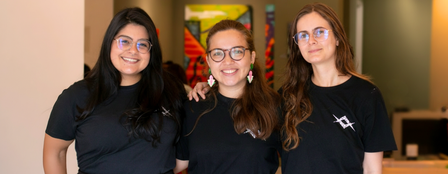 Equipe Raio que o Parta, formada por três jovens usando camisetas pretas e óculos. Gabrielle Arnour, Elisa Malcher e Elis Almeida