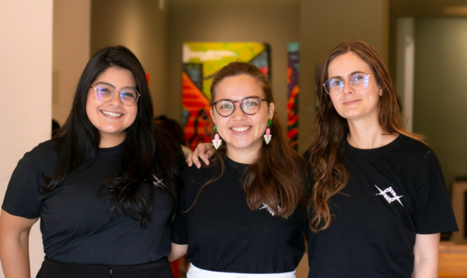 Equipe Raio que o Parta, formada por três jovens usando camisetas pretas e óculos. Gabrielle Arnour, Elisa Malcher e Elis Almeida
