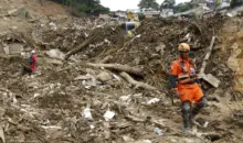 Deslizamento de terra na cidade de Petrópolis causado por risco de deslizamentos, com estruturas destruídas e equipes de resgate no local.
