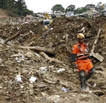 Deslizamento de terra na cidade de Petrópolis causado por risco de deslizamentos, com estruturas destruídas e equipes de resgate no local.
