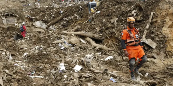 Deslizamento de terra na cidade de Petrópolis causado por risco de deslizamentos, com estruturas destruídas e equipes de resgate no local.