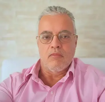 Ednildo Machado, biólogo formado pela Universidade do Estado do Rio de Janeiro (UERJ), posando em ambiente interno com parede de fundo neutra.