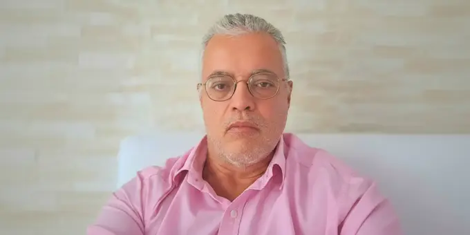 Ednildo Machado, biólogo formado pela Universidade do Estado do Rio de Janeiro (UERJ), posando em ambiente interno com parede de fundo neutra.