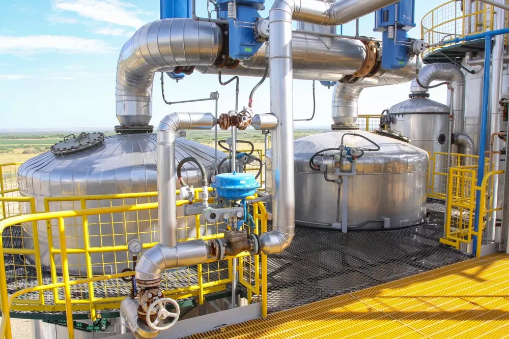 Infraestrutura de produção de etanol com tanques e tubulações de aço inox na usina de combustível renovável, destacando tecnologia avançada na indústria de biocombustíveis.