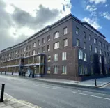 Arquitetura moderna no Appleby Blue em Londres, destacando o design que evita afastar a velhice do centro da cidade, com fachada de tijolos escuros e janelas amplas.