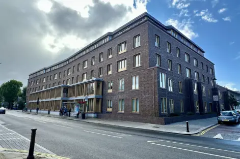 Arquitetura moderna no Appleby Blue em Londres, destacando o design que evita afastar a velhice do centro da cidade, com fachada de tijolos escuros e janelas amplas.