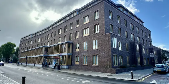 Arquitetura moderna no Appleby Blue em Londres, destacando o design que evita afastar a velhice do centro da cidade, com fachada de tijolos escuros e janelas amplas.