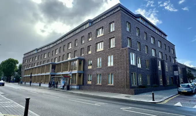 Arquitetura moderna no Appleby Blue em Londres, destacando o design que evita afastar a velhice do centro da cidade, com fachada de tijolos escuros e janelas amplas.