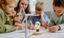 Crianças participando de uma atividade educativa sobre energias renováveis em sala de aula, com foco na adaptação climática das cidades usando fontes sustentáveis.