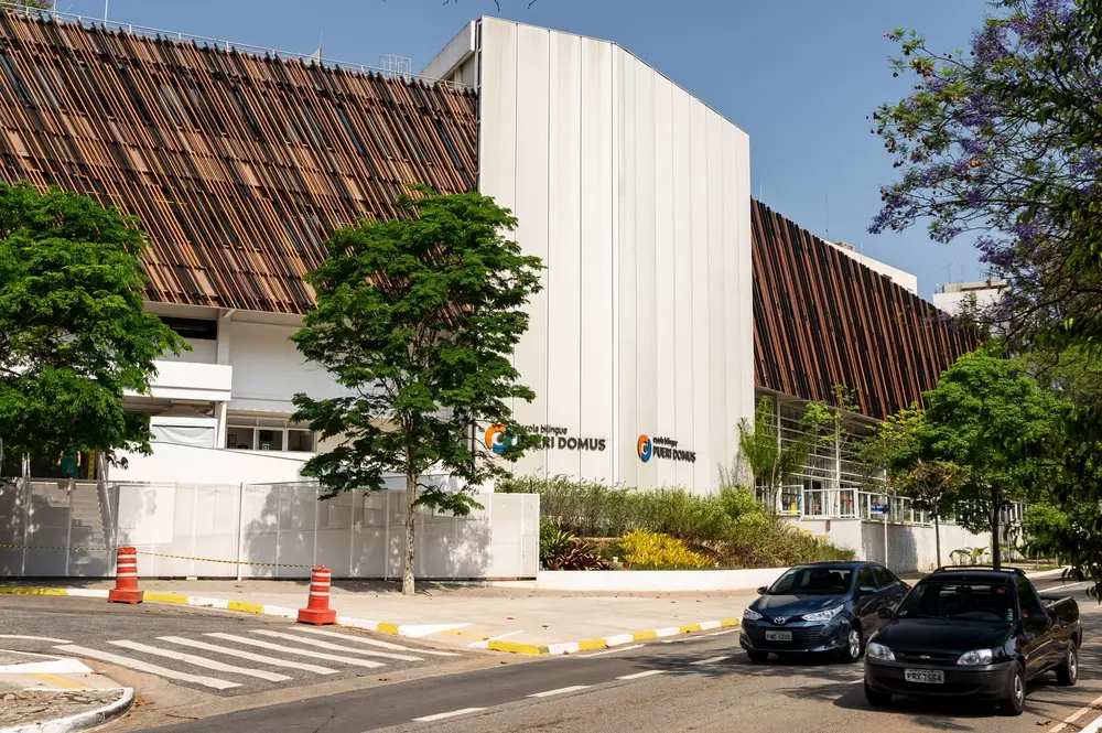 Fachada do prédio da escola bilíngue Pueri Domus, localizada na esquina da rua Ministro Godoi com a avenida Sumaré, sob um céu azul e ensolarado.