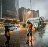 Pedestres enfrentam chuva e queda de temperatura no centro de São Paulo, simbolizando a importância do urbanismo inteligente para cidades mais resilientes e sustentáveis.