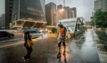 Pedestres enfrentam chuva e queda de temperatura no centro de São Paulo, simbolizando a importância do urbanismo inteligente para cidades mais resilientes e sustentáveis.