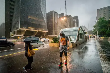 Pedestres enfrentam chuva e queda de temperatura no centro de São Paulo, simbolizando a importância do urbanismo inteligente para cidades mais resilientes e sustentáveis.