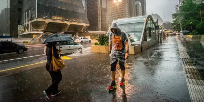 Pedestres enfrentam chuva e queda de temperatura no centro de São Paulo, simbolizando a importância do urbanismo inteligente para cidades mais resilientes e sustentáveis.