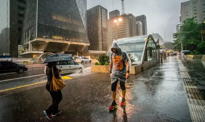 Pedestres enfrentam chuva e queda de temperatura no centro de São Paulo, simbolizando a importância do urbanismo inteligente para cidades mais resilientes e sustentáveis.