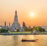 Pôr do sol dourado sobre o rio Chao Phraya e Wat Arun, onde uma nova ponte-jardim conectará as margens para pedestres.