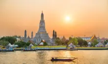 Pôr do sol dourado sobre o rio Chao Phraya e Wat Arun, onde uma nova ponte-jardim conectará as margens para pedestres.