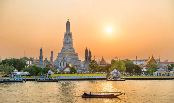 Pôr do sol dourado sobre o rio Chao Phraya e Wat Arun, onde uma nova ponte-jardim conectará as margens para pedestres.