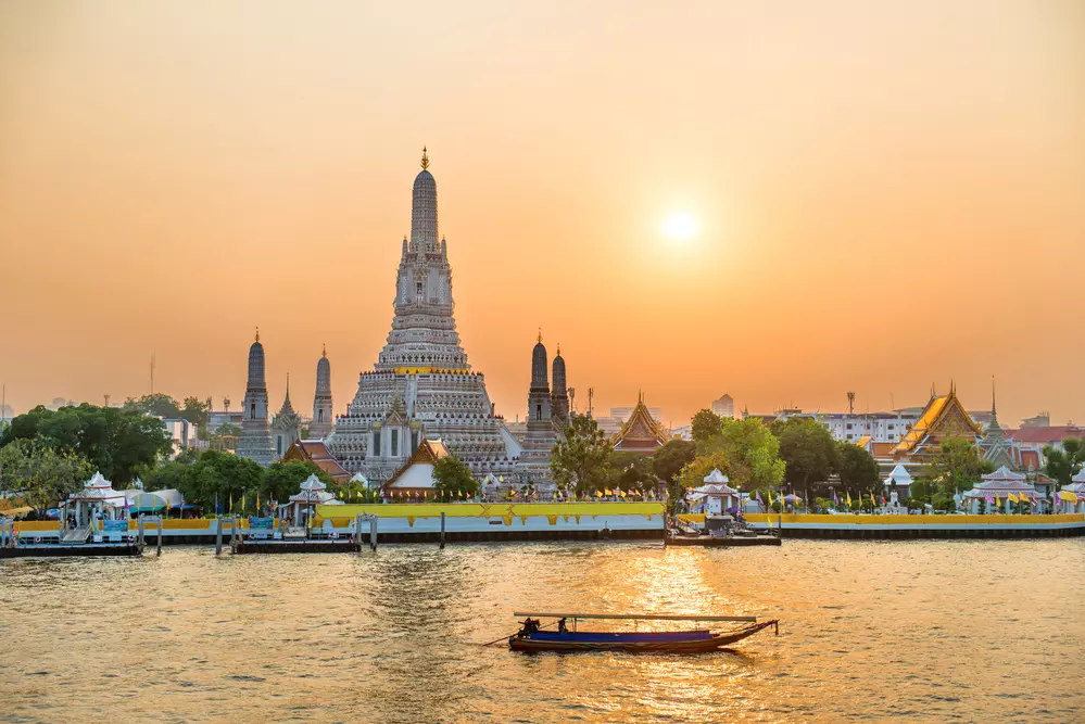 Pôr do sol dourado sobre o rio Chao Phraya e Wat Arun, onde uma nova ponte-jardim conectará as margens para pedestres.