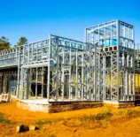 Estrutura de Steel Frame para construção a seco de uma casa moderna em andamento, com estrutura metálica visível, em terreno ao ar livre.
