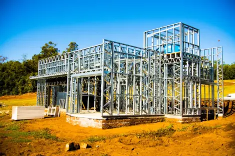 Estrutura de Steel Frame para construção a seco de uma casa moderna em andamento, com estrutura metálica visível, em terreno ao ar livre.