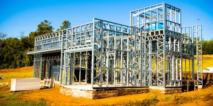 Estrutura de Steel Frame para construção a seco de uma casa moderna em andamento, com estrutura metálica visível, em terreno ao ar livre.